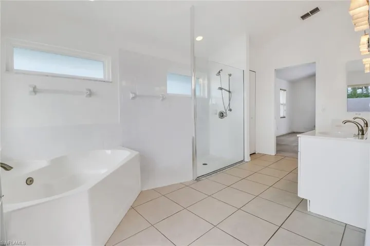 Bathroom with shower with separate bathtub, tile patterned floors, and vanity