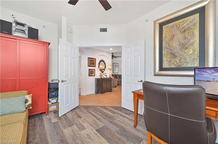 Interior space featuring wood-finish flooring, white walls, and a ceiling fan