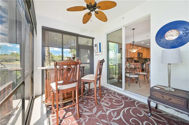 Screened lanai featuring a ceiling fan, sliding glass door access to the interior, and a partial outdoor landscape