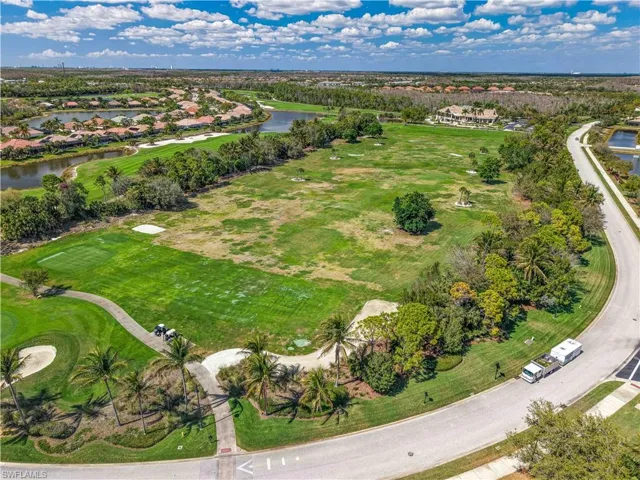 Expansive golf course property featuring manicured greens, mature trees, a paved cart path, and perimeter waterways