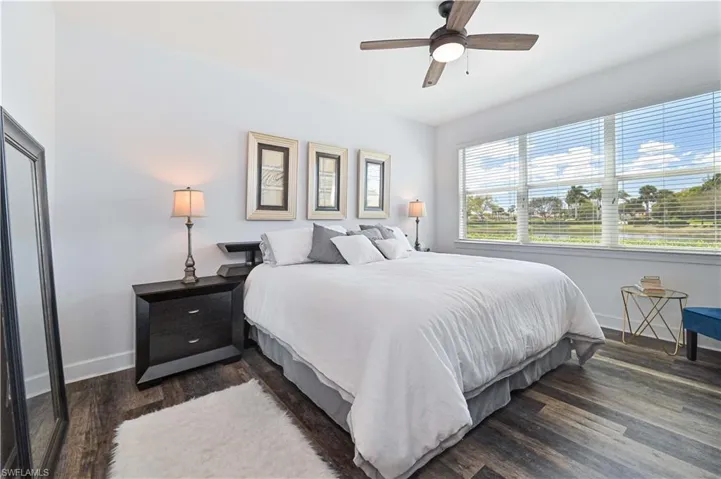 Bright interior featuring large windows with blinds, wood-finish flooring, a ceiling fan with integrated lighting, and white walls