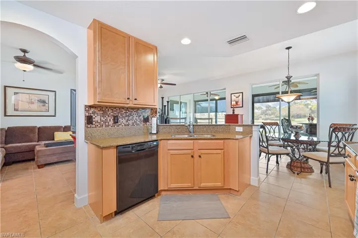 Kitchen featuring light wood-finish cabinetry, granite-style countertops, and a mosaic tile backsplash
