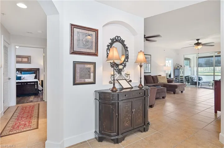 Open concept floor plan featuring tile flooring throughout main living areas, a hallway leading to a separate room with wood-finish flooring, and expansive sliding glass doors providing abundant natural light