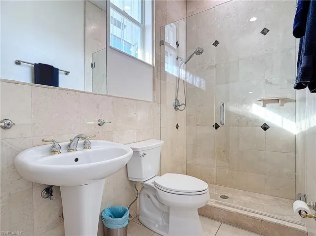 Full bathroom with tile walls, a shower stall, and tile patterned flooring