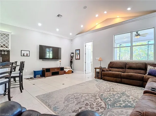 Living room with vaulted ceiling, ornamental molding, recessed lighting, light tile patterned flooring, and a ceiling fan