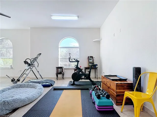 Exercise area featuring light tile patterned flooring and baseboards