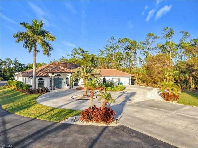Mediterranean / spanish-style house with concrete driveway, a tiled roof, a front lawn, and stucco siding