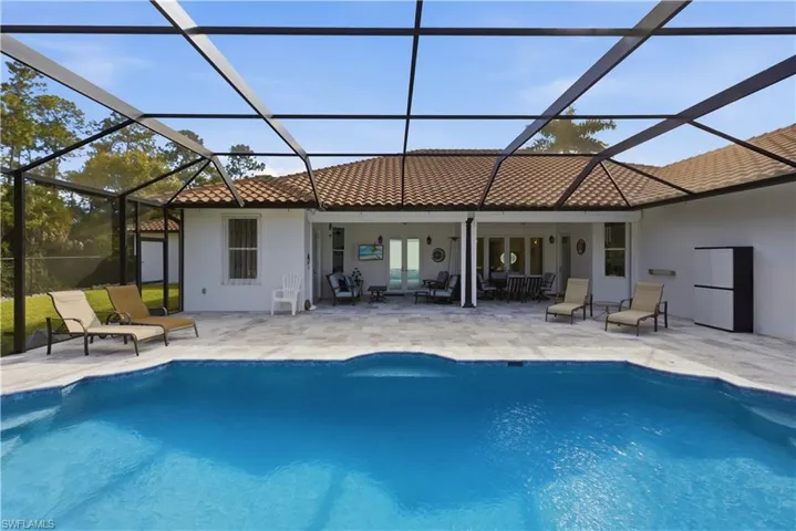 Rear view of house featuring a sunroom, a patio area, and stucco siding