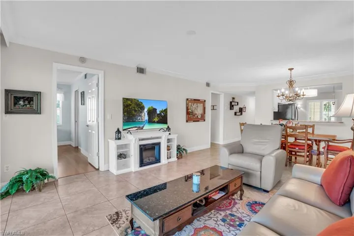 Living room with crown molding, a chandelier, and light tile floors