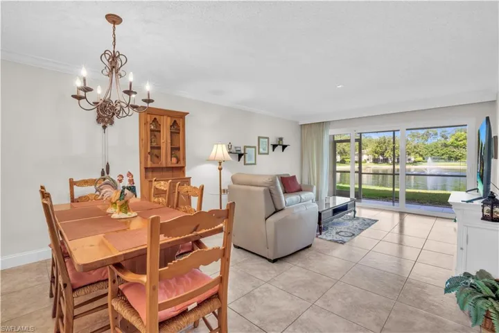 Tiled dining space featuring ornamental molding, a water view, and an inviting chandelier