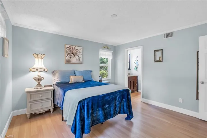 Master Bedroom with a textured ceiling, ensuite bathroom, crown molding, and light wood-type flooring