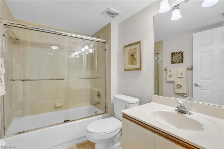 Full bathroom with combined bath / shower with glass door, oversized vanity, toilet, and tile floors