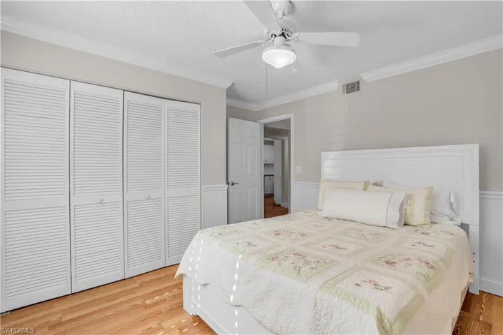 Bedroom 2 with a closet, ceiling fan, light wood-type flooring, and crown molding