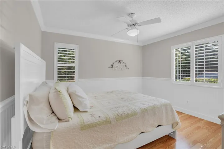 Bedroom 2 with ceiling fan, light hardwood / wood-style flooring, a textured ceiling, and ornamental molding
