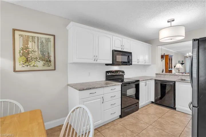 Kitchen featuring black appliances, white cabinetry, and light tile floors