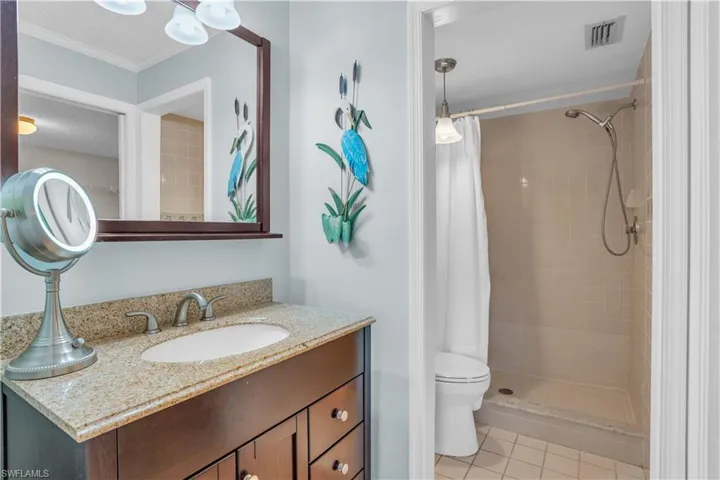 Bathroom featuring a textured ceiling, curtained shower, tile floors, vanity, and toilet