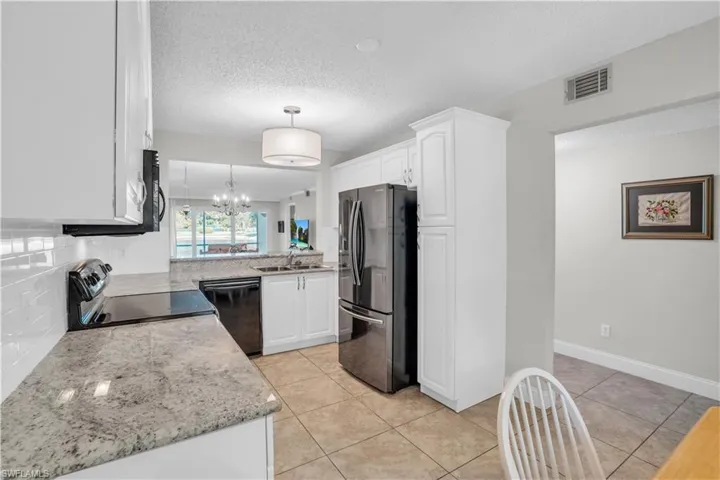Kitchen featuring white cabinets, range, backsplash, stainless steel refrigerator, and dishwasher