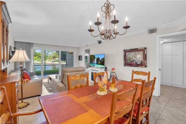 Tiled dining area featuring a chandelier and crown molding