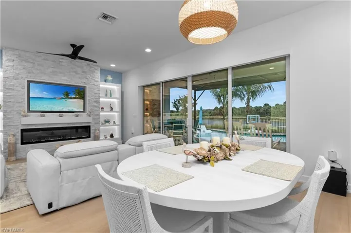 Dining area with light wood-type flooring, a fireplace, built in shelves, a ceiling fan, and recessed lighting