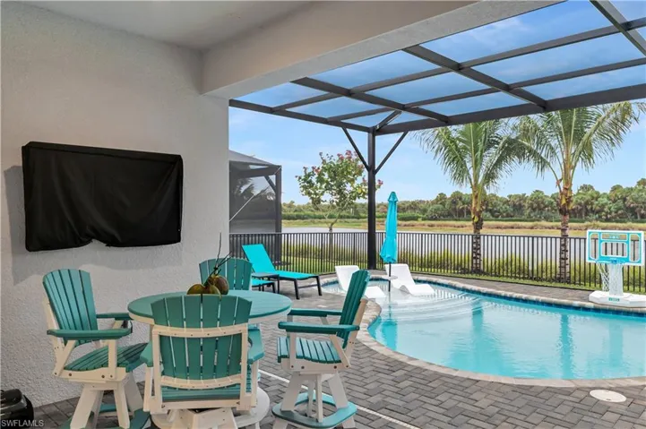 View of pool featuring a patio, a lanai, outdoor dining space, and a water view