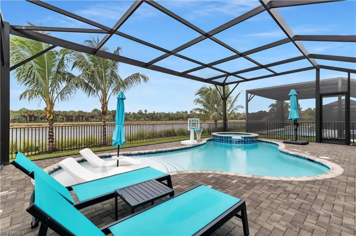 View of pool featuring a pool with connected hot tub, a patio, a lanai, a water view, and a fenced backyard