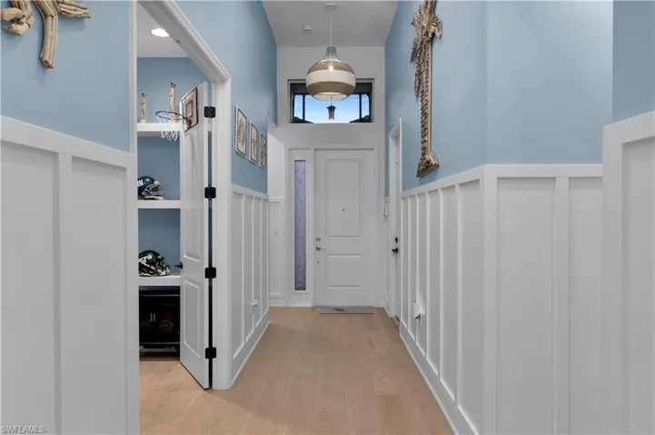 Foyer featuring a wainscoted wall, light wood-style floors, and a decorative wall