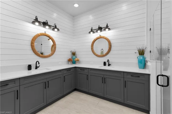 Bathroom featuring double vanity, a shower stall, and wood walls