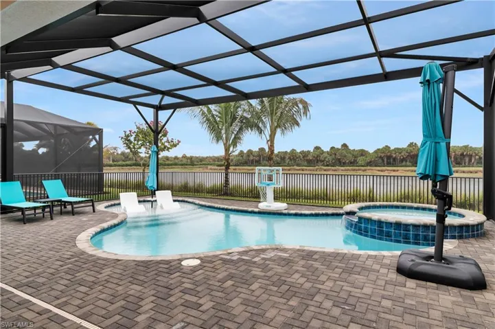 View of swimming pool featuring a lanai, a sunroom, a patio area, a pool with connected hot tub, and a water view