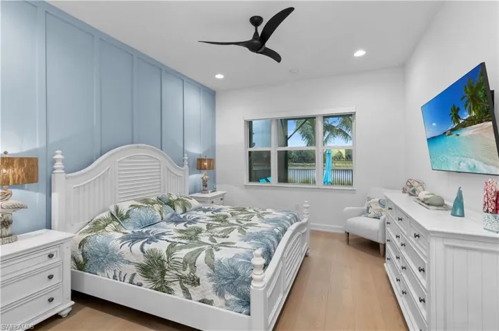 Bedroom with a decorative wall, light wood finished floors, ceiling fan, and recessed lighting
