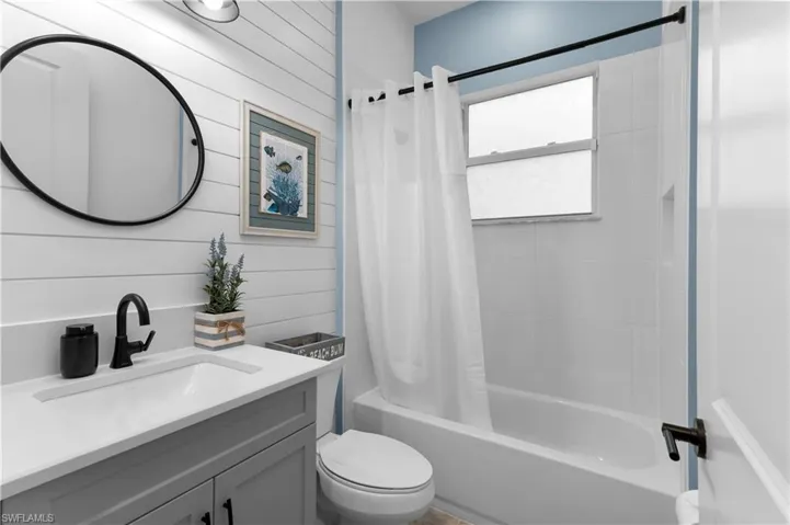 Bathroom with shower / bath combo, vanity, and wooden walls