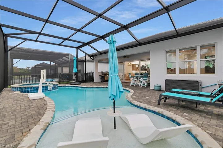View of pool featuring a lanai, a sunroom, a patio, a pool with connected hot tub, and a grill