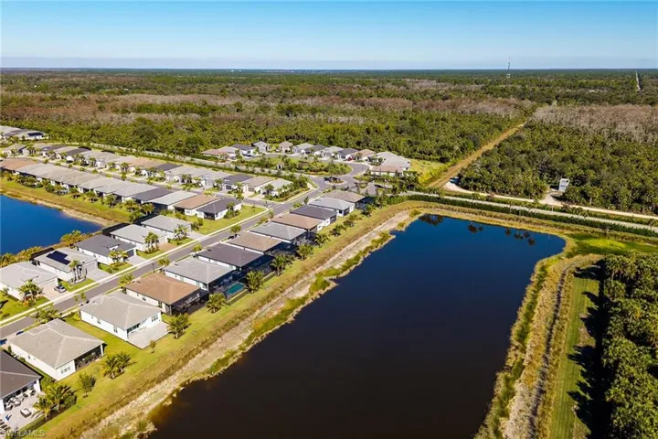 Aerial view of residential area with a nearby body of water and a heavily wooded area