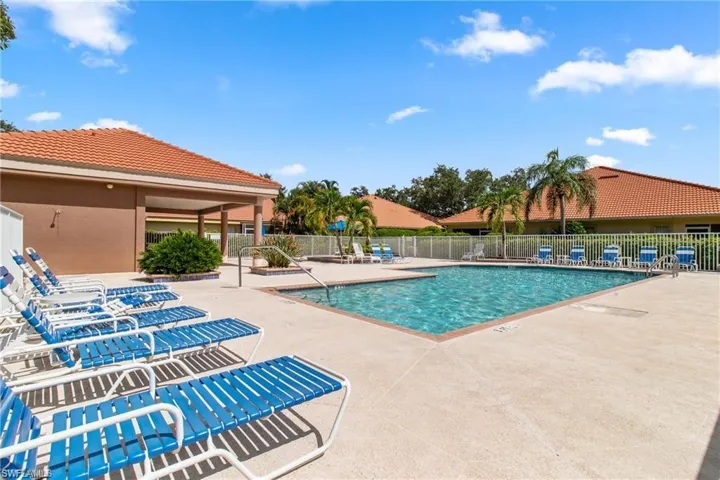 Outdoor swimming pool with concrete decking and surrounding white fencing