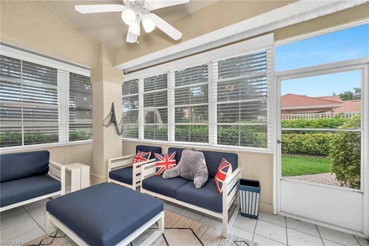Screened porch featuring a white ceiling fan with integrated lighting, white-framed windows with blinds, a screen door, and tile flooring