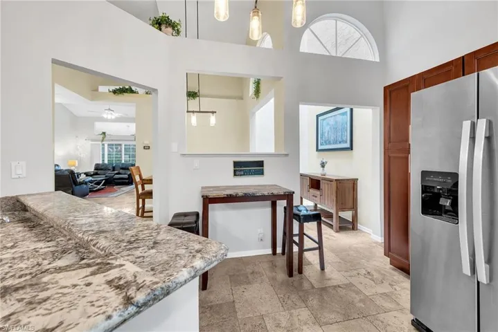 Kitchen featuring stainless steel refrigerator, warm wood cabinetry, and a granite-style countertop