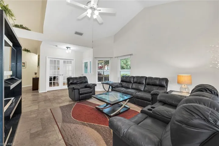 Living area featuring high vaulted ceilings, ceiling fan, tile flooring, and white French doors