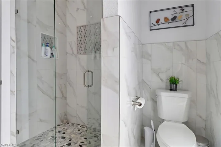 Full bathroom featuring a marble finish shower and tile walls