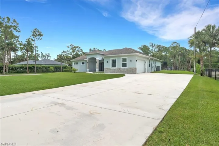 Prairie-style house with a front yard, stone siding, driveway, stucco siding, and a garage