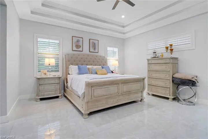 Bedroom featuring ceiling fan, ornamental molding, and a tray ceiling