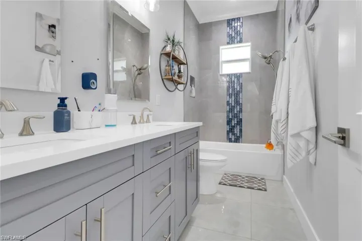 Bathroom featuring tub / shower combination, double vanity, and light tile patterned flooring
