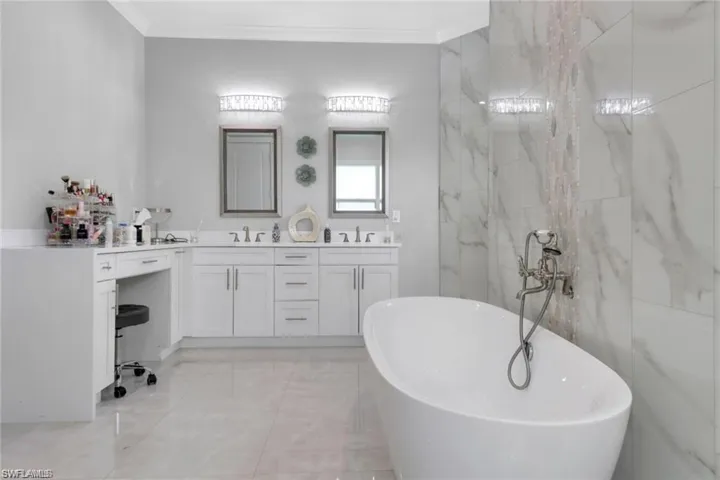 Bathroom with double vanity, a freestanding bath, and ornamental molding