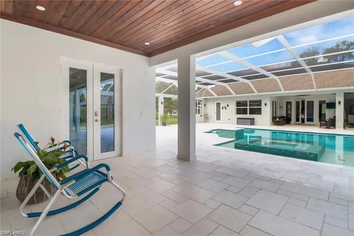 Combined pool / hot tub with french doors, a patio area, glass enclosure, and a sunroom