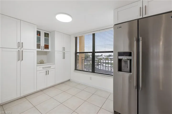 Kitchen featuring light tile patterned floors, white cabinetry, and stainless steel fridge with ice dispenser
