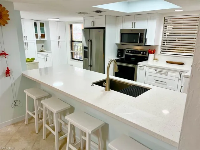 Kitchen featuring a breakfast bar, sink, appliances with stainless steel finishes, and white cabinets