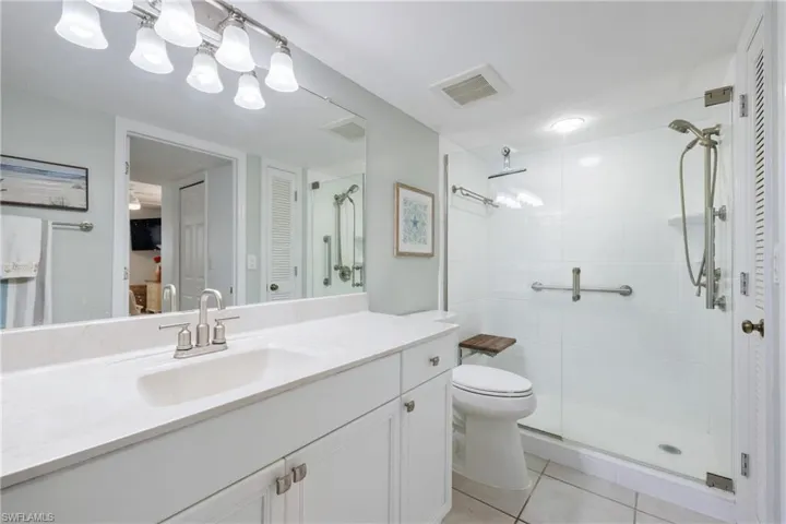 Bathroom with walk in shower, tile patterned flooring, vanity, and toilet