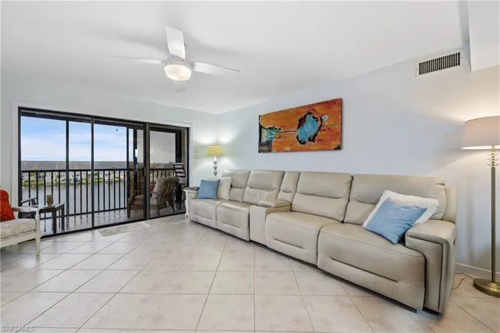 Living room with a water view, ceiling fan, and light tile patterned floors