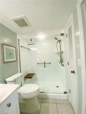 Bathroom featuring vanity, toilet, a shower with shower door, and tile patterned floors