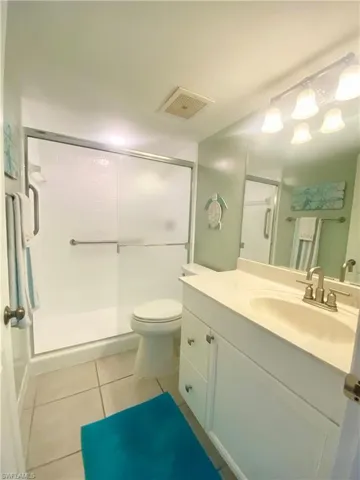 Bathroom featuring vanity, toilet, an enclosed shower, and tile patterned floors