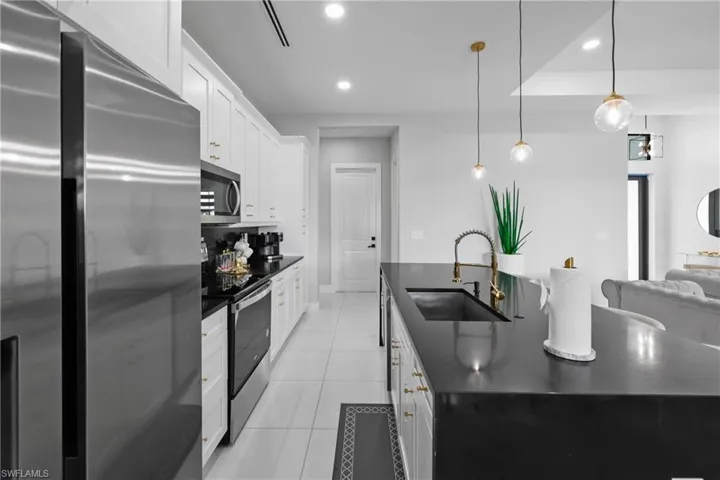 Kitchen with appliances with stainless steel finishes, pendant lighting, light tile patterned floors, white cabinetry, and recessed lighting