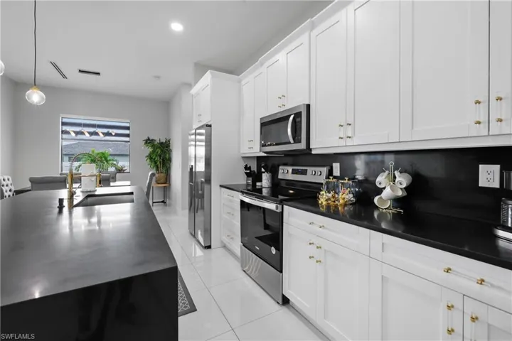 Kitchen featuring appliances with stainless steel finishes, pendant lighting, light tile patterned floors, white cabinetry, and recessed lighting